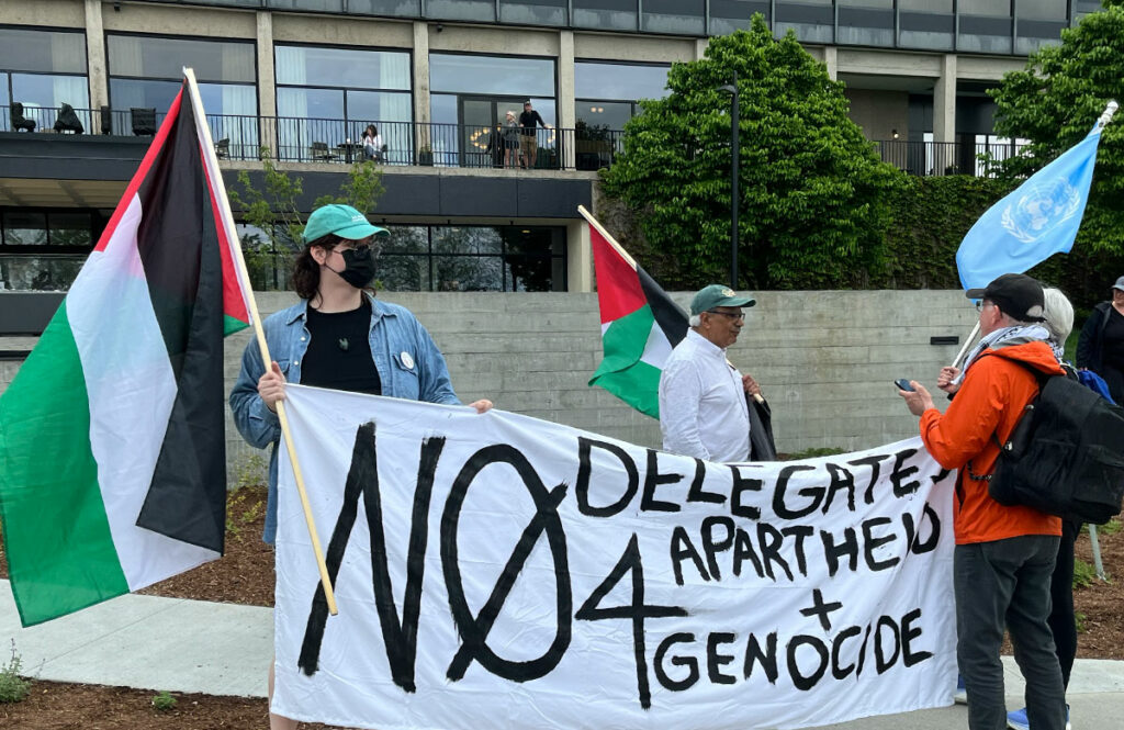 Vermonters holding a "No Delegates for Apartheid and Genocide" sign outside the Lake Champlain Hilton on Saturday.